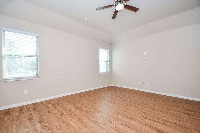 empty room with ceiling fan, a raised ceiling, and light hardwood / wood-style flooring