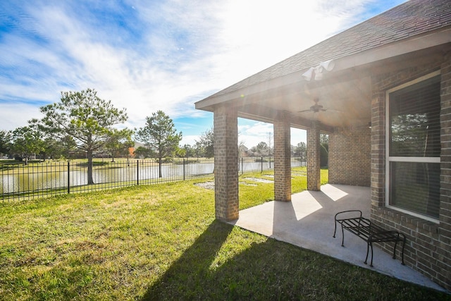 view of yard featuring a water view, ceiling fan, and a patio