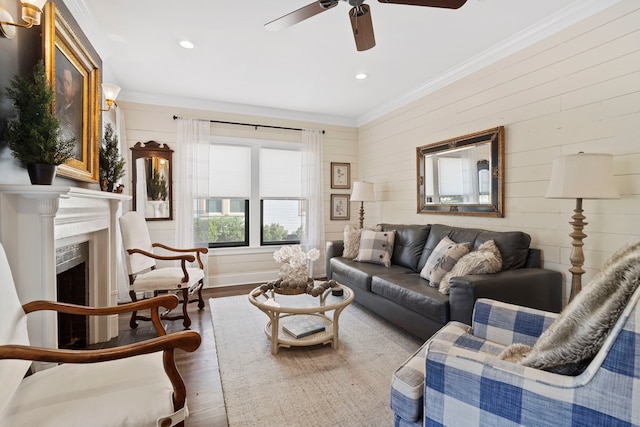 living room with ceiling fan, wood walls, wood-type flooring, and ornamental molding