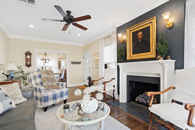 living room with ceiling fan, wood walls, dark hardwood / wood-style flooring, and crown molding