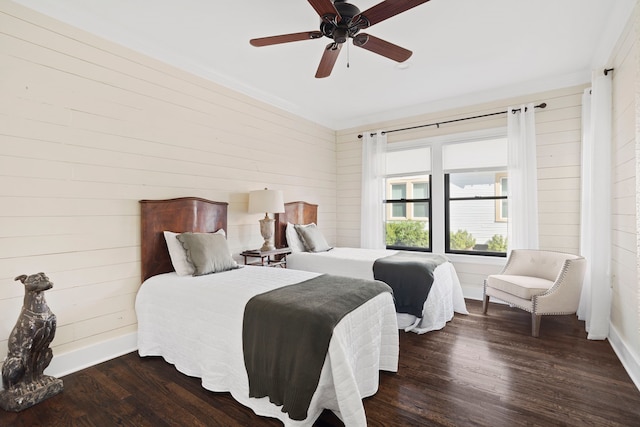 bedroom featuring ceiling fan, dark wood-type flooring, and wood walls