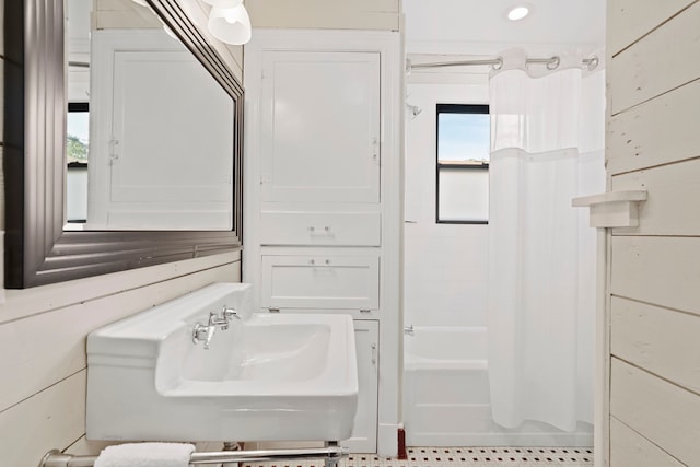 bathroom featuring shower / tub combo, sink, and wood walls