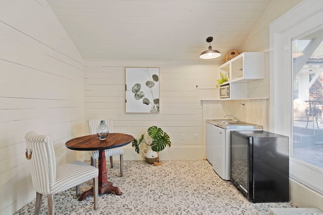 laundry area featuring cabinets, wooden walls, and washing machine and clothes dryer