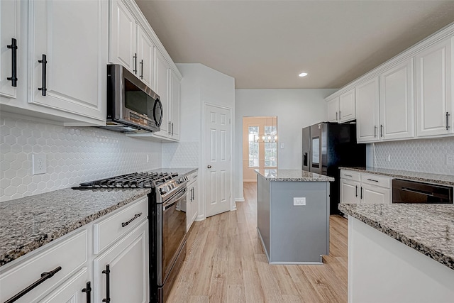 kitchen featuring white cabinetry, light stone counters, light hardwood / wood-style flooring, and stainless steel appliances