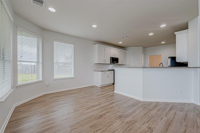 kitchen featuring white cabinets, sink, light hardwood / wood-style flooring, light stone counters, and kitchen peninsula