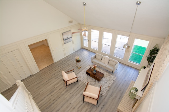 living room with ceiling fan, light hardwood / wood-style flooring, and high vaulted ceiling