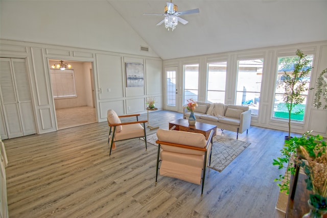 living room with ceiling fan with notable chandelier, light wood-type flooring, and high vaulted ceiling