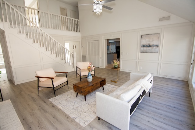 living room with ceiling fan, light hardwood / wood-style flooring, and high vaulted ceiling