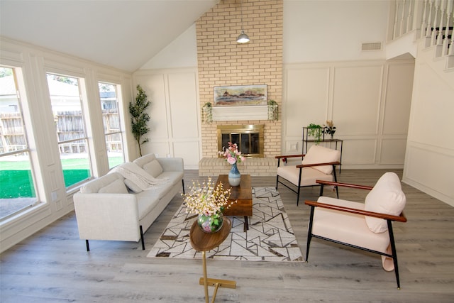 interior space with a fireplace, high vaulted ceiling, and light hardwood / wood-style flooring