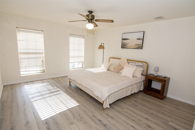 bedroom featuring ceiling fan, light hardwood / wood-style flooring, and multiple windows