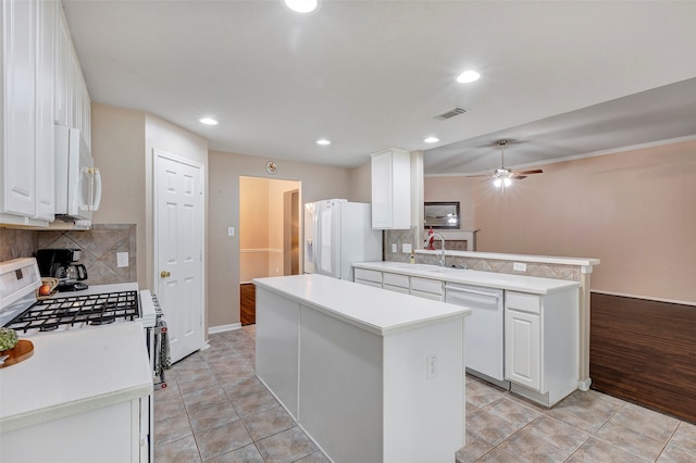 kitchen with decorative backsplash, white appliances, sink, white cabinets, and a kitchen island