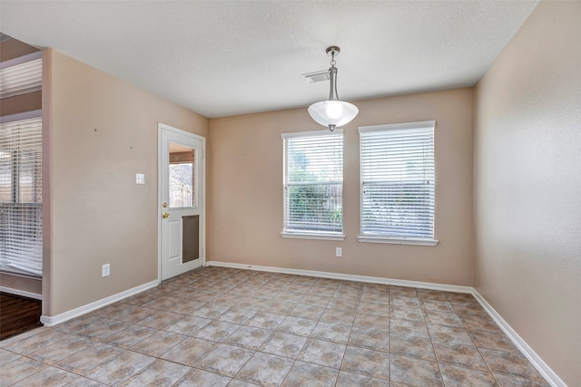 spare room with light tile patterned floors and a textured ceiling