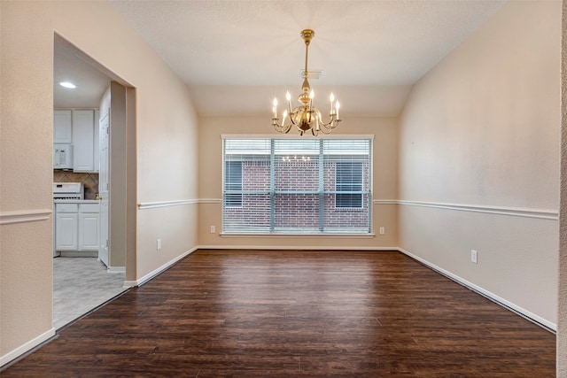 unfurnished dining area featuring wood-type flooring, vaulted ceiling, and an inviting chandelier