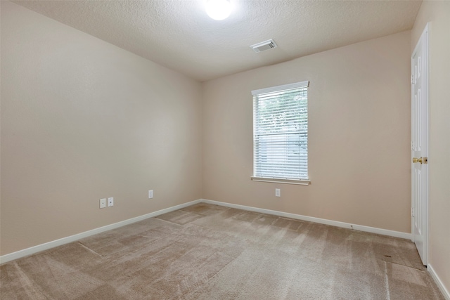 empty room with light colored carpet and a textured ceiling