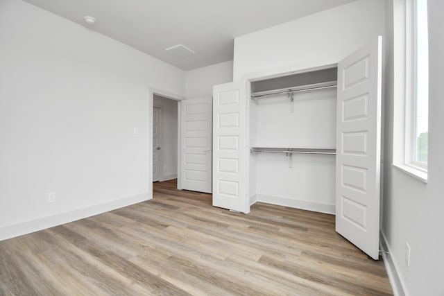 unfurnished bedroom with a closet and light hardwood / wood-style flooring