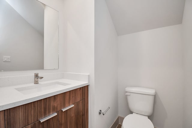 bathroom featuring toilet, vanity, and vaulted ceiling