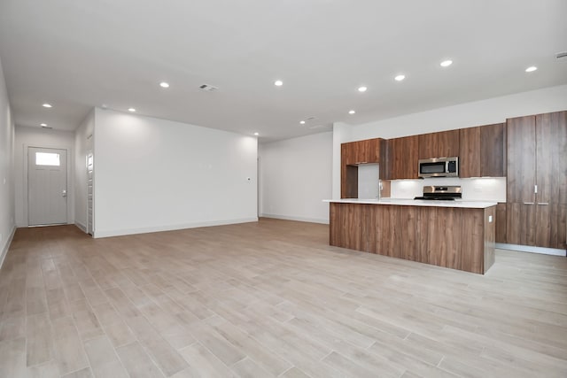 kitchen with a center island with sink, light hardwood / wood-style flooring, and appliances with stainless steel finishes