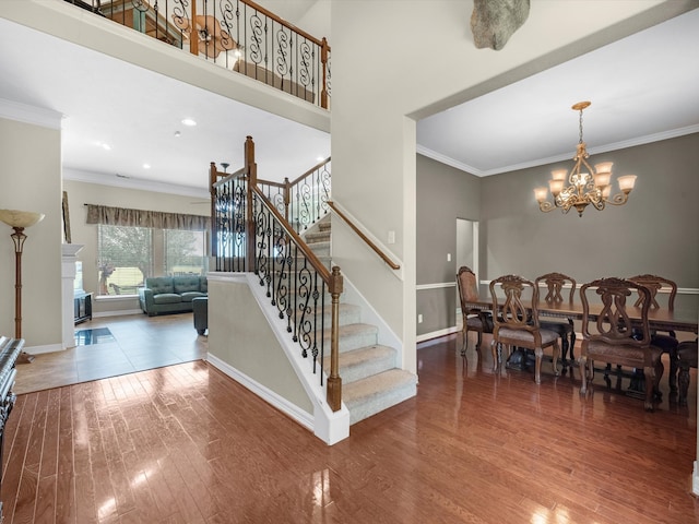 staircase with crown molding, hardwood / wood-style floors, and an inviting chandelier