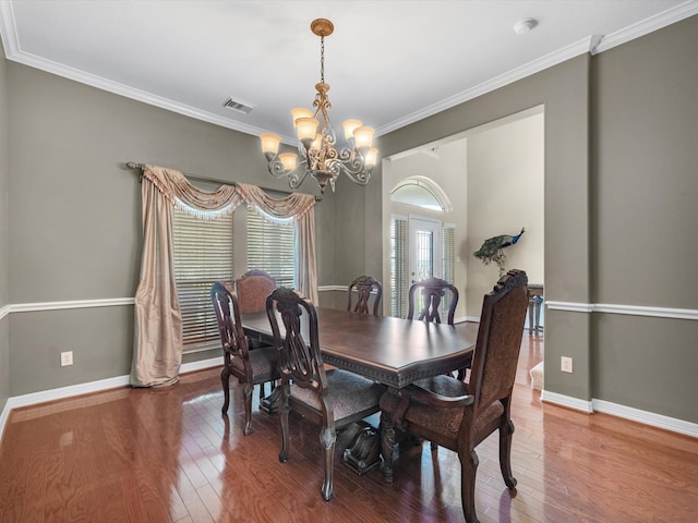 dining space featuring crown molding, hardwood / wood-style floors, and a notable chandelier