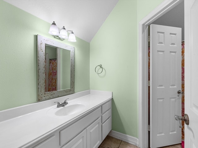 bathroom featuring tile patterned flooring, vanity, and vaulted ceiling