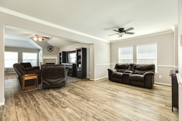 living room with light wood-type flooring, vaulted ceiling, ceiling fan, and ornamental molding