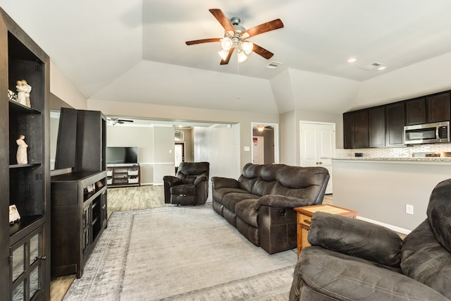 living room featuring ceiling fan, light wood-type flooring, and vaulted ceiling