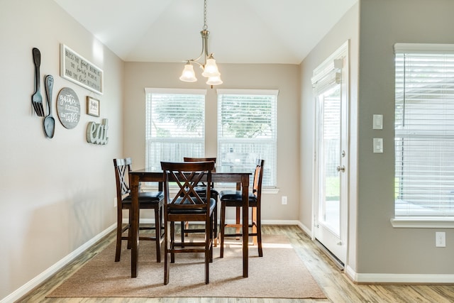 dining room featuring a healthy amount of sunlight, light hardwood / wood-style flooring, and lofted ceiling