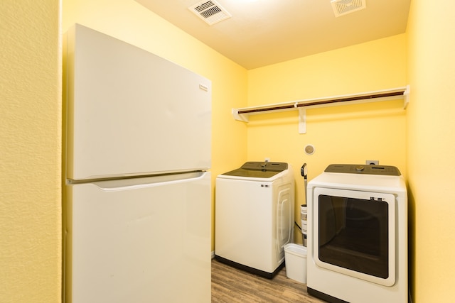 clothes washing area with washing machine and dryer and light wood-type flooring