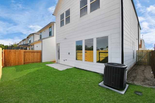 back of house with central AC unit and a lawn