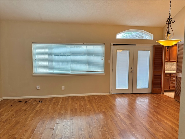 interior space with french doors, a textured ceiling, and light hardwood / wood-style floors