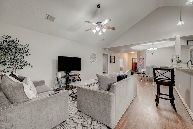 living room featuring ceiling fan with notable chandelier, light hardwood / wood-style floors, and high vaulted ceiling