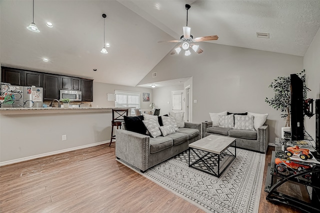 living room featuring ceiling fan, sink, high vaulted ceiling, and light hardwood / wood-style flooring