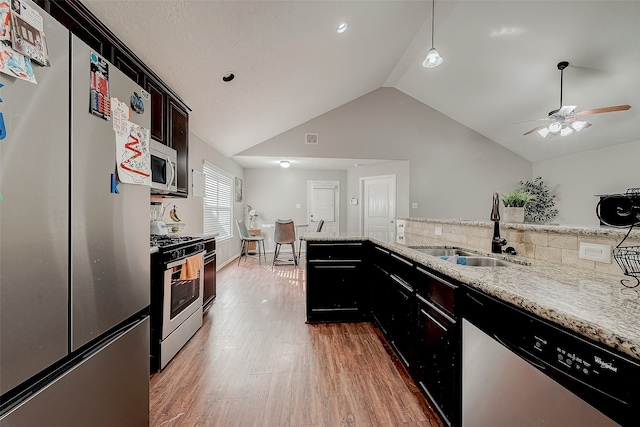 kitchen featuring ceiling fan, sink, light stone countertops, hardwood / wood-style floors, and appliances with stainless steel finishes