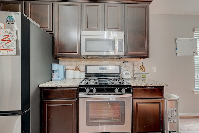 kitchen featuring decorative backsplash, light hardwood / wood-style floors, dark brown cabinetry, and appliances with stainless steel finishes