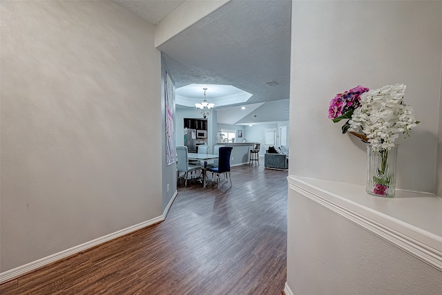 corridor with an inviting chandelier, a textured ceiling, and hardwood / wood-style flooring