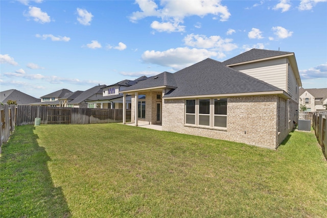 back of property with central air condition unit and a yard