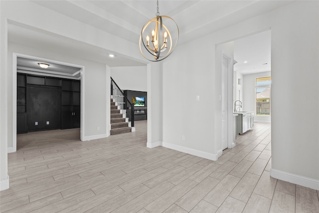 empty room with sink, a notable chandelier, and light wood-type flooring