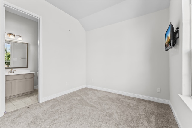 carpeted empty room with lofted ceiling and sink