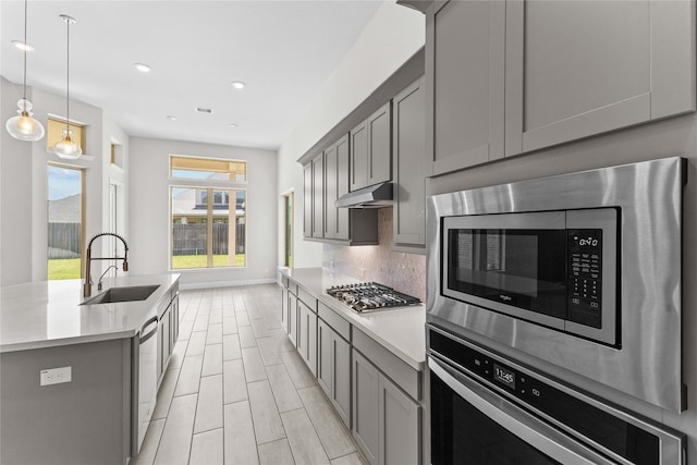 kitchen with sink, stainless steel appliances, tasteful backsplash, pendant lighting, and gray cabinets