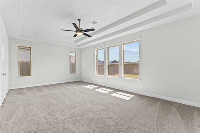 unfurnished room featuring a raised ceiling, ceiling fan, and carpet flooring