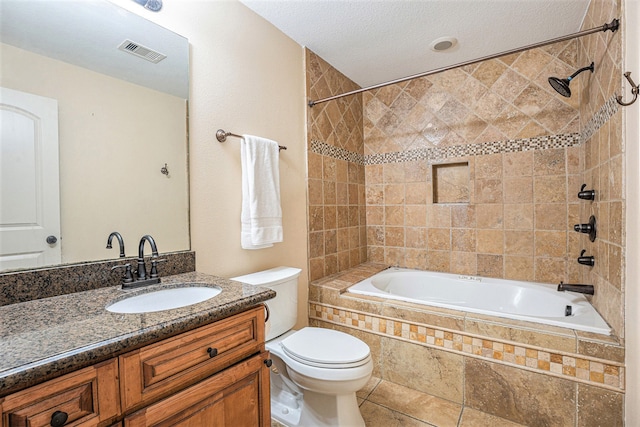 full bathroom featuring vanity, tile patterned floors, tiled shower / bath, toilet, and a textured ceiling