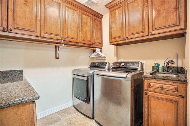 laundry area featuring washing machine and dryer, sink, light tile patterned flooring, and cabinets