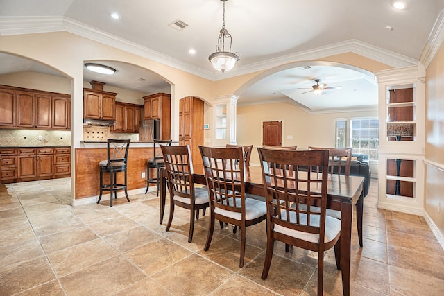 dining room with ceiling fan, decorative columns, ornamental molding, and lofted ceiling