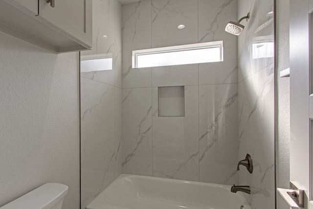 bathroom featuring toilet and tiled shower / bath