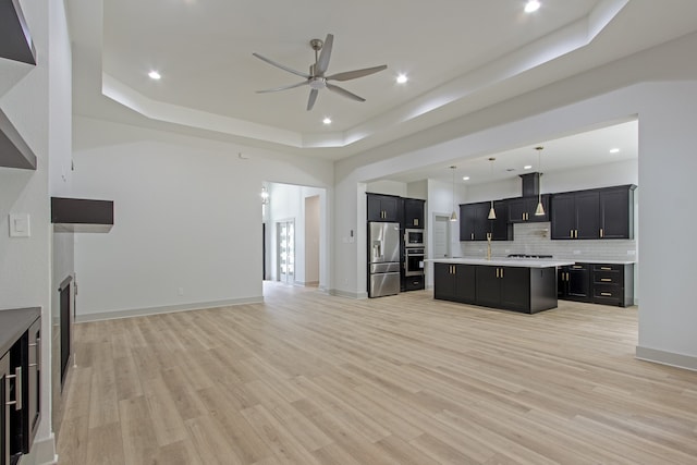 unfurnished living room with light hardwood / wood-style floors, a raised ceiling, and ceiling fan