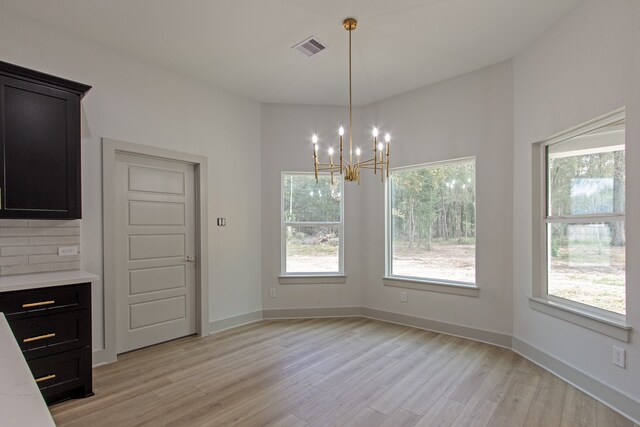 unfurnished dining area with a chandelier, light wood-type flooring, and a healthy amount of sunlight