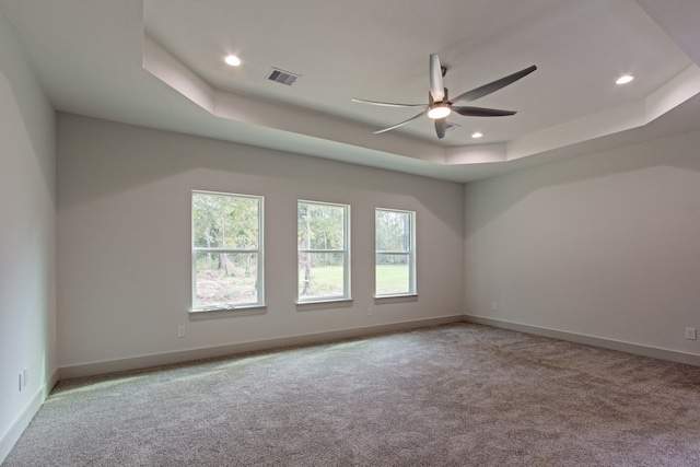 carpeted spare room featuring ceiling fan and a tray ceiling