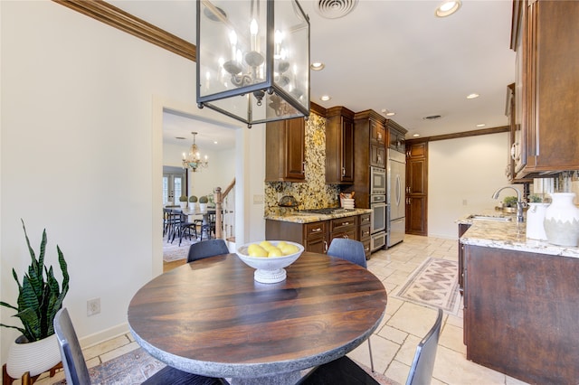 dining space featuring ornamental molding, sink, and a chandelier