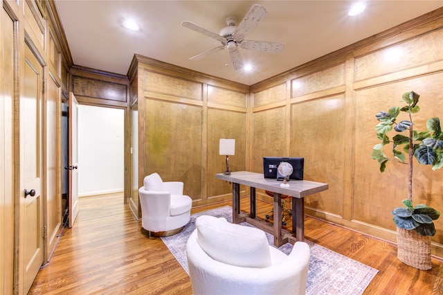 home office featuring light hardwood / wood-style flooring, ceiling fan, and wooden walls