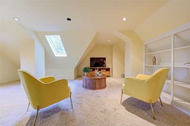 living area with vaulted ceiling with skylight and light colored carpet